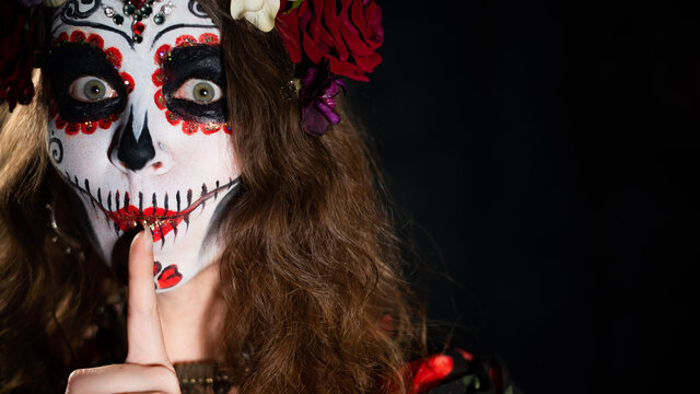 Woman in santa muerte makeup on a black background. Girl wearing traditional mexican holy death costume for halloween. Copy space
