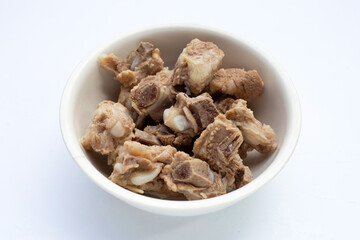 Boiled pork ribs in white bowl on white background.
