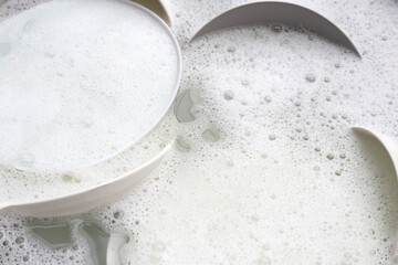 Washing dishes, Close up of utensils soaking in kitchen sink.