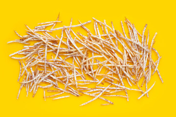 Fried taro sticks on yellow background.