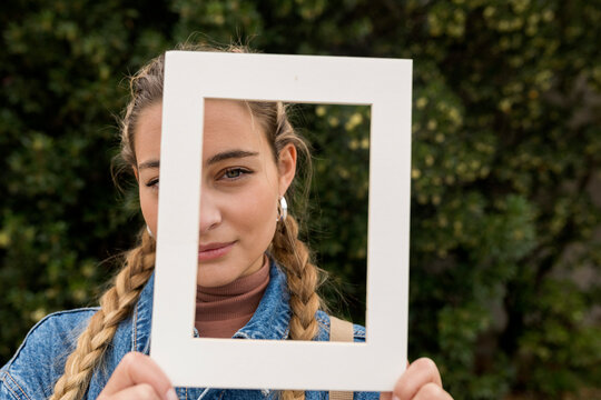 Young woman looking through white frame
