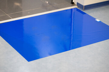 Blue Adhesive Sticky Mats for disinfection at hospital entrance.
