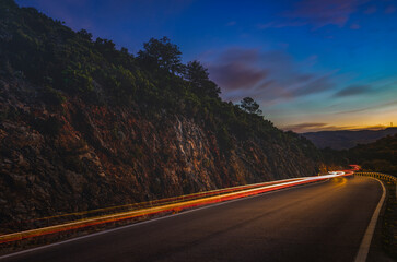 night mountain road with car lights trail