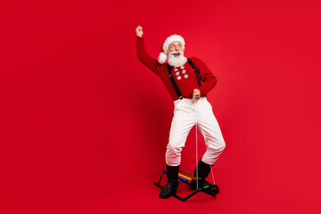 Fototapeta na wymiar Full length body size view of carefree cheerful Santa sleighing isolated over bright red color background