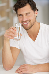 happy man drinking water in kitchen