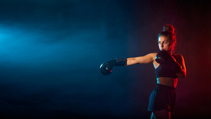 Boxing. Young woman athletic female MMA fighter training. Concept of sport, competition, action, healthy lifestyle. Copy space for ad.