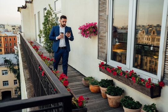 Male professional using smart phone while walking in office balcony