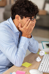 stressed businessman at desk with head in his hands