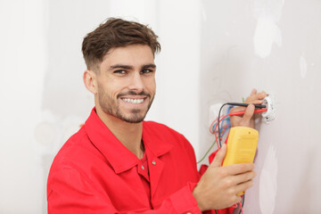 happy electrician checking socket voltage
