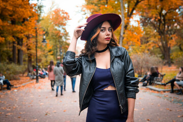Young fashion woman in casual clothes and black leather jacket over urban city background autumn portrait. Hipster girl posing at street. Fashionable long hair model in elegant autumn clothes. hat.