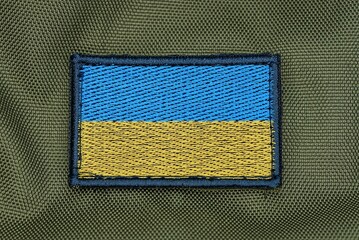 one rectangular blue yellow patch of the Ukrainian flag on the green fabric of the backpack