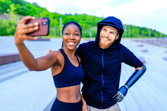 mixed race friends fitness training together outdoors taking selfie photo on smartphone camera