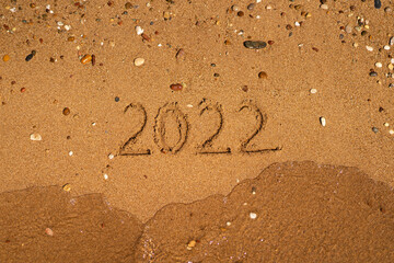 Happy New Year 2022 on the beach. Sand on a beach with a wave by the sea. Winter Vacation on the sea. New Year concept. Top view