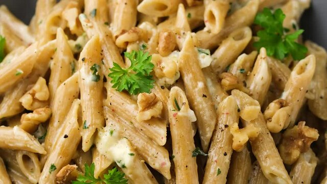 Penne pasta with gorgonzola cheese sauce and walnut. Rotating video.
