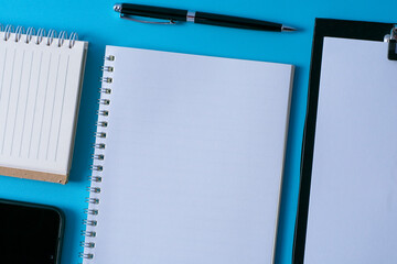 Top view of blank open notebook on blue background and different objects. Minimal flat lay style.