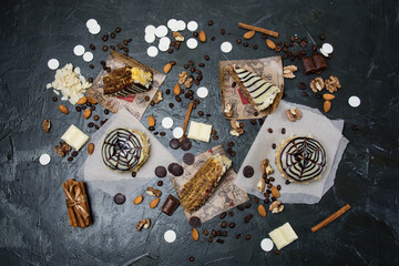 Lots of pastries and cakes, chocolate, frosting and cinnamon top view on a dark background, copy space