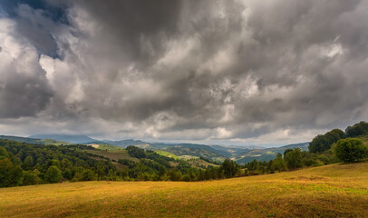 Obraz premium Autumn mountain landscape - yellowed and reddened autumn trees combined with green needles and blue skies. Colorful autumn landscape scene in the Romanian Carpathians. Panoramic view.