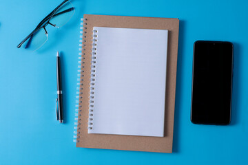 Top view of blank open notebook on blue background and different objects. Minimal flat lay style.