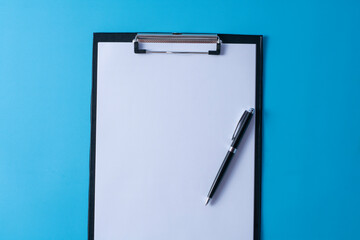 Top view of blank paper on clipboard on blue background and different objects. Minimal flat lay style.