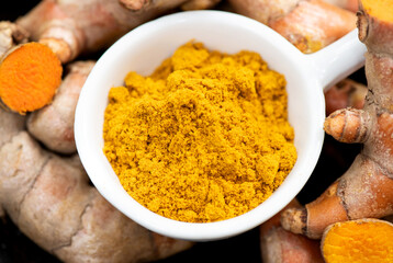 Turmeric rhizome and powder on nature background.