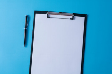 Top view of blank paper on clipboard on blue background and different objects. Minimal flat lay style.