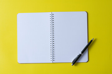 Top view of blank open notebook on yellow background and different objects. Minimal flat lay style.