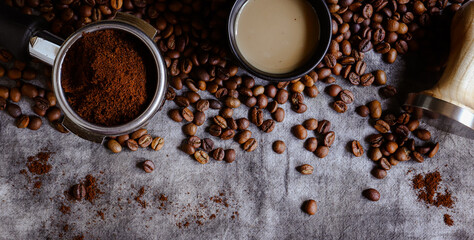 Fresh roasted coffee background. Banner. Tamper and portafilter on a gray linen background.