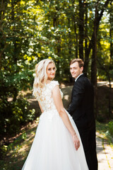 Bride and groom at wedding day walking outdoors on summer nature. Stylish and beautiful. Bridal couple. Loving wedding couple outdoor