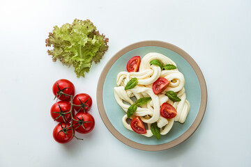 Soft cecil cheese with basil leaves and fresh tomatoes, top view