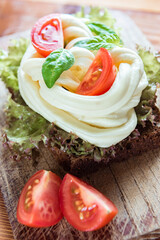 Homemade chechil cheese with fresh tomatoes, lettuce and basil leaves on wooden board, selective focus