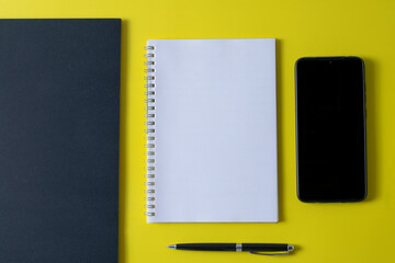 Top view of blank open notebook on yellow background and different objects. Minimal flat lay style.