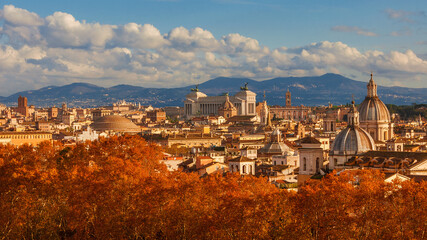 Fototapeta na wymiar Autumn in Rome. View of the historical center skyline just before sunset with old monuments, baroque domes and red leaves