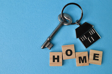 Top view of key, toy house and square letters with text HOME