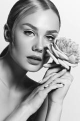 Portrait of a beautiful young woman with perfect smooth skin and blond hair. Woman holding  flower in her hands. Cosmetics advertising concept. Natural composition. Face and body skin care.я