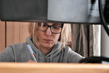 Young woman with glasses is working at a computer at home.