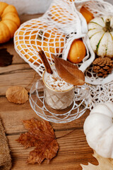 Autumn art composition - hot drink, varied dried leaves, pumpkins on wooden background, cozy autumn