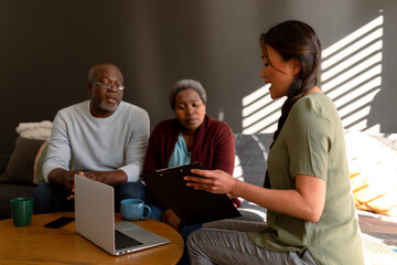 African american senior couple having meeting with asian female financial advisor at home