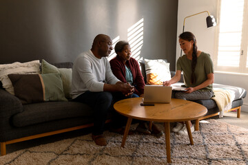 African american senior couple having meeting with asian female financial advisor at home