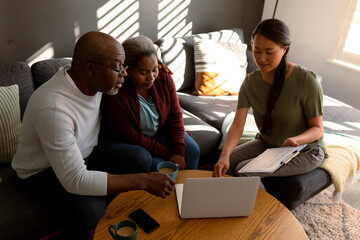 African american senior couple having meeting with asian female financial advisor at home