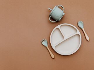 Composition with baby food accessory on brown background. Neutral pastel colors