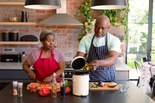 Serious African American Senior Couple Cooking Together In Kitchen Using Compost Bin