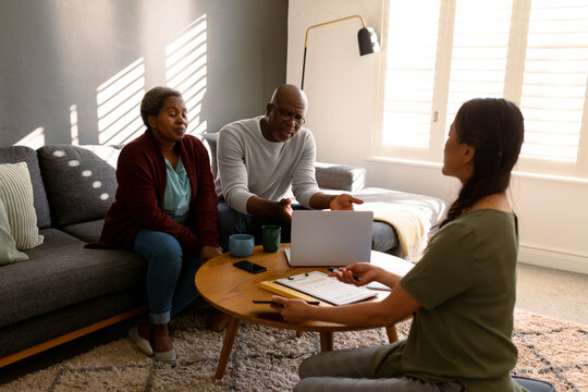 African American Senior Couple Having Meeting With Asian Female Financial Advisor At Home