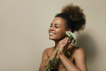 A beautiful young woman with a high hairstyle and curly hair laughs. A woman holds a white flower in her hands. Natural cosmetic. Natural makeup. 