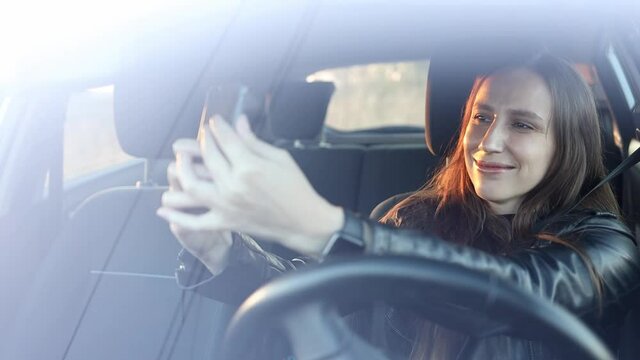 Cheerful young woman taking selfie sitting in the car.