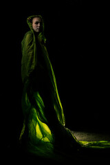 Girl posing in green draping on dark background