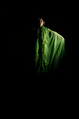 Girl posing in green draping on dark background