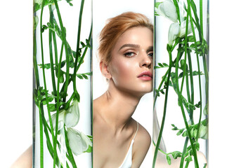 Young red-haired woman close-up on a white background.Hands hug vases with bouquets of white...