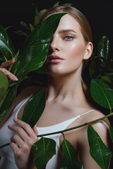 A beautiful tanned young woman with natural makeup and smooth hair stands in the jungle among exotic plants. Tropical plants, nature.Advertising spa and natural cosmetics.