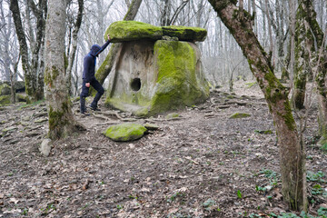 Tourist (man) looking at dolmen Mother's heart in Pshada village on cloudy winter day. Krasnodar Krai, Caucasus, Russia.