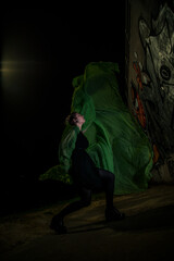 Girl posing in green draping on dark background